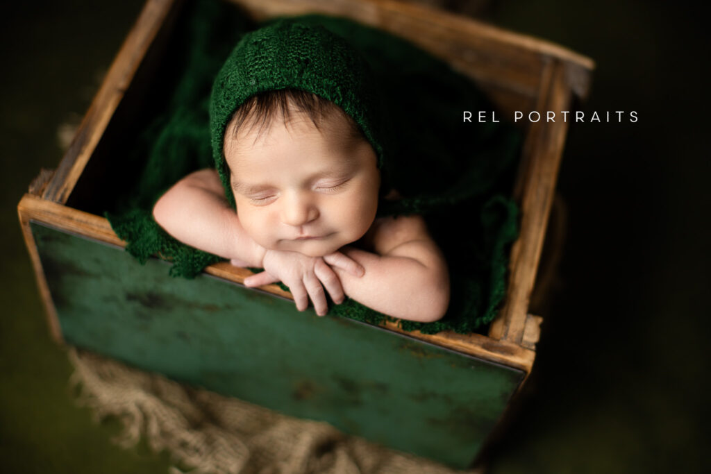 Newborn baby boy wearing a bonnet in green 