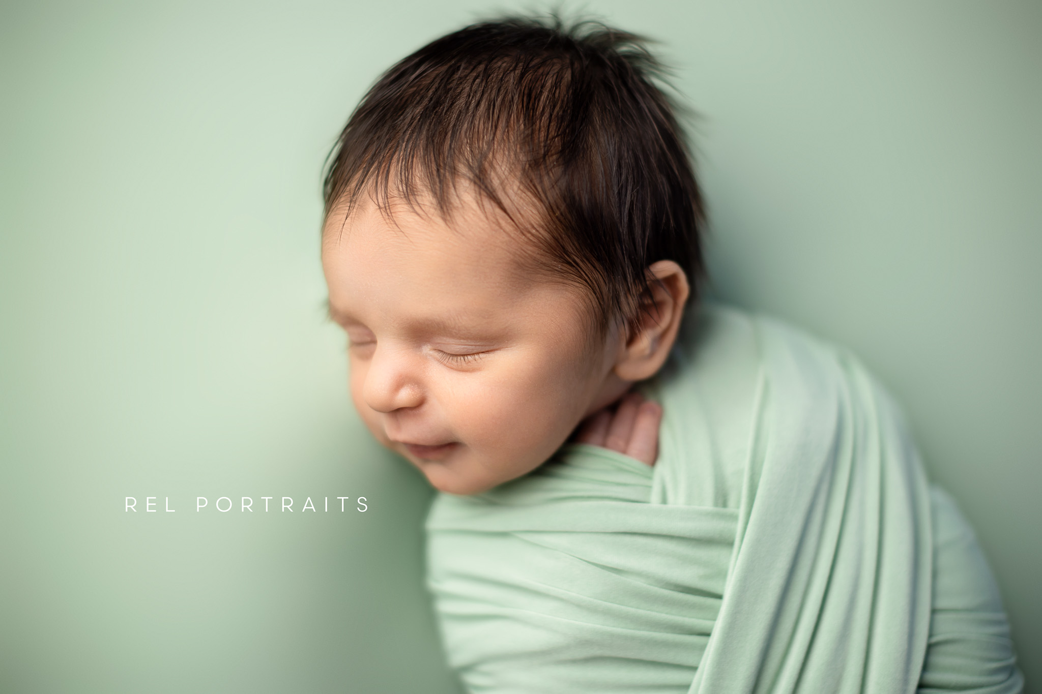 newborn Baby boy wrapped in green smirking