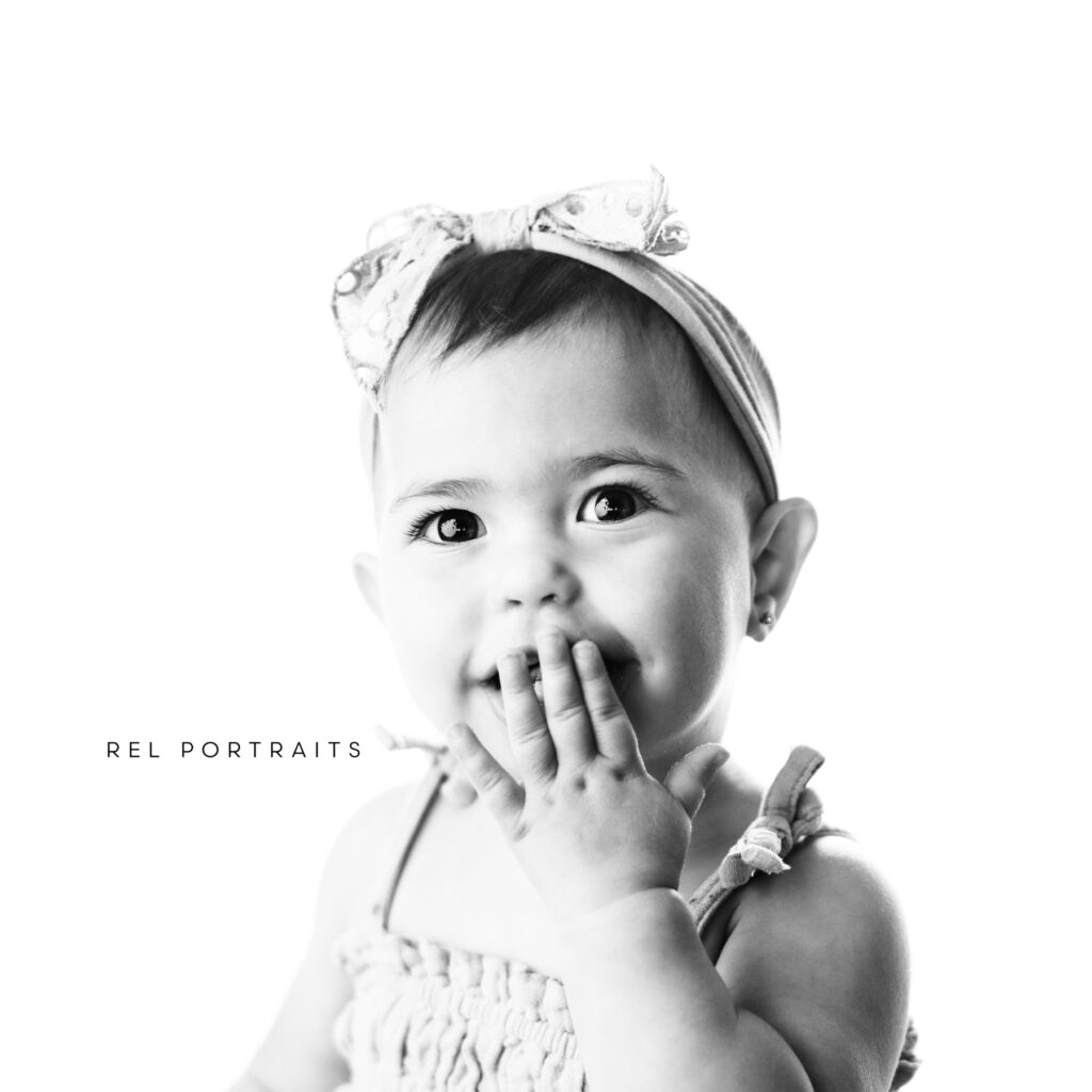 baby girl with hand over mouth at milestone session