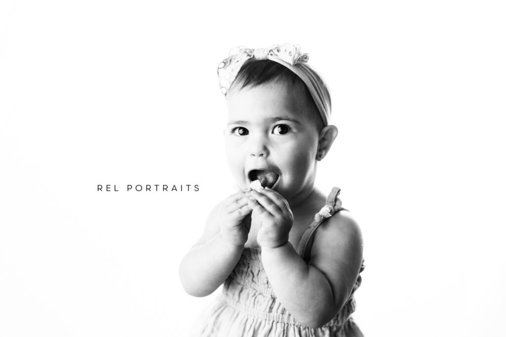 baby girl eating a cookie in black and white