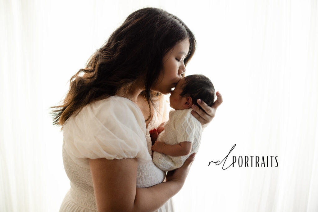 photoshoot of Mom kissing Newborn 