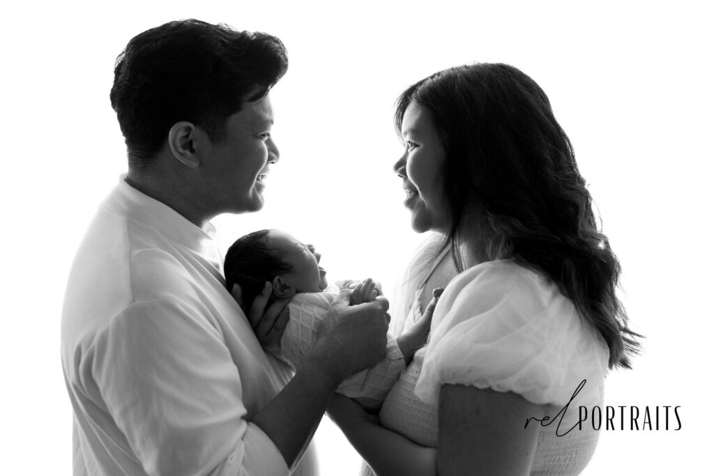 newborn and family in black and white backlit