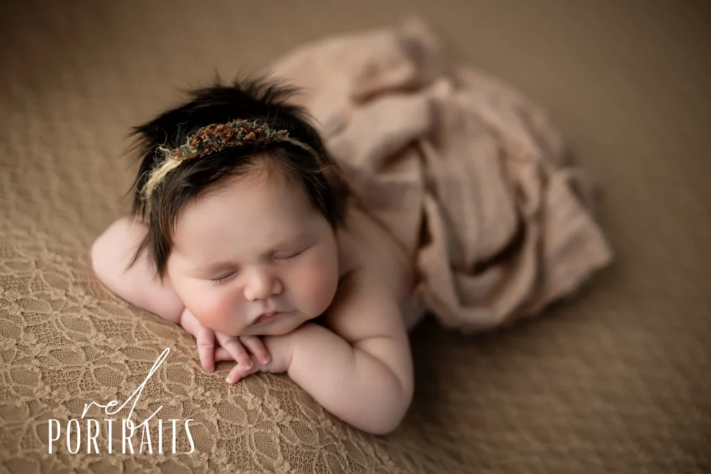 Newborn baby girl in brown laying down