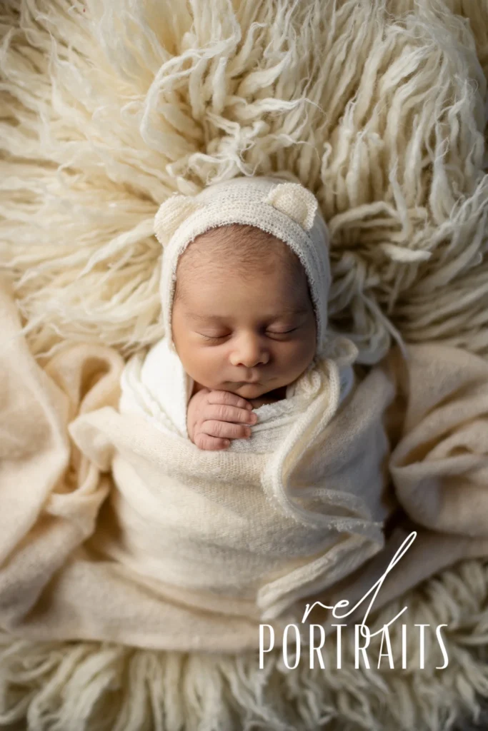 Baby boy in bear hat on cream rug