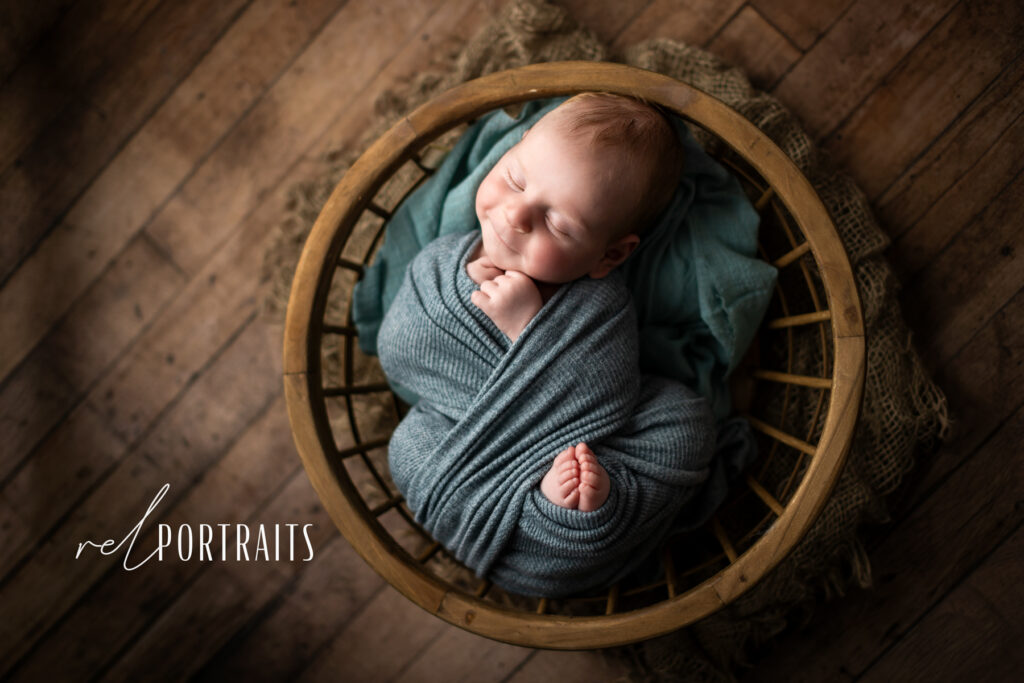 adorable newborn baby boy smiling in a bowl