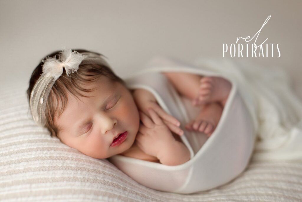 newborn baby girl at photoshoot cream backdrop